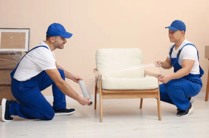 Movers wrapping furniture with protective padding.